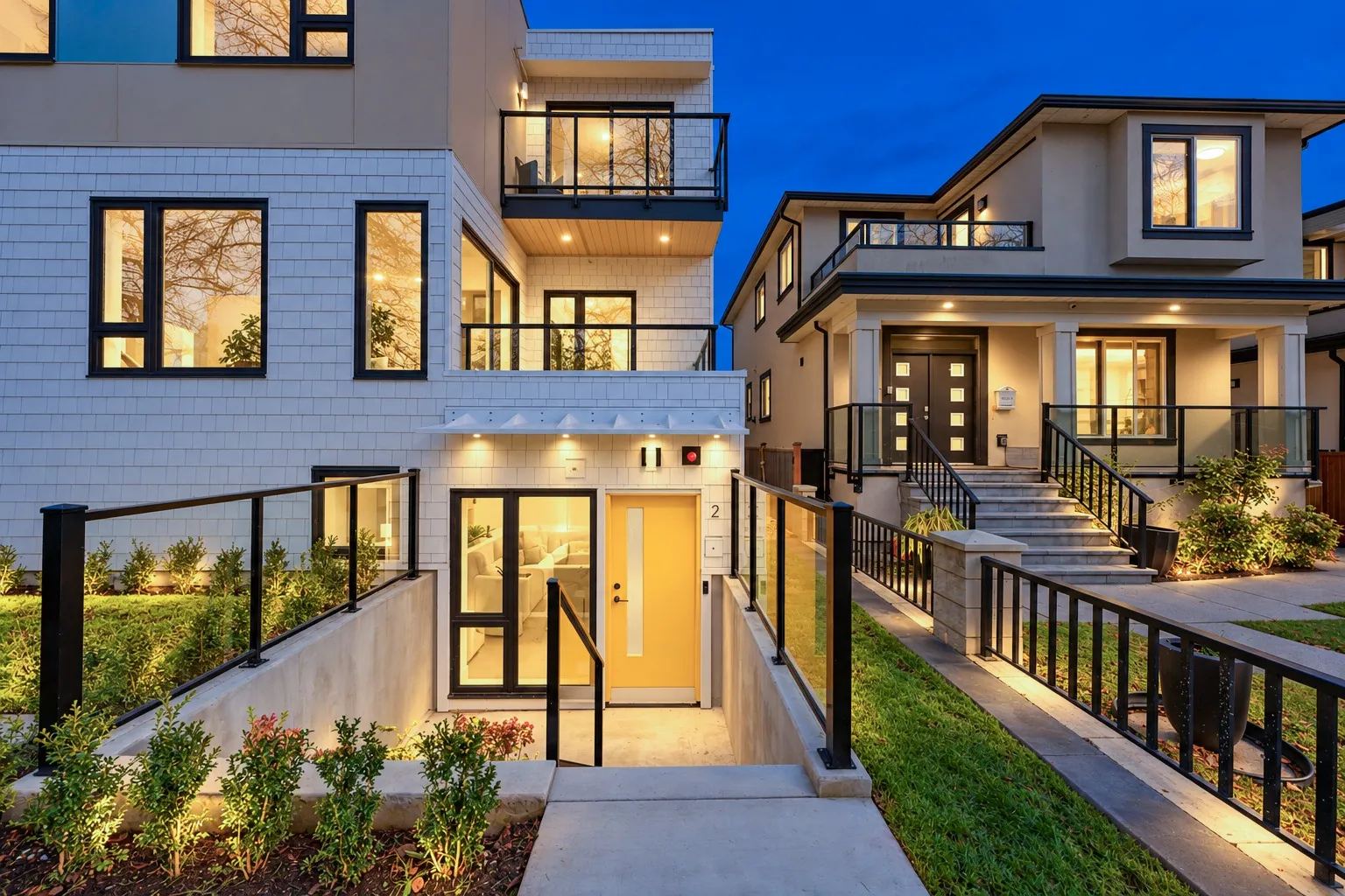 The same view at dusk: the door and the window lit, lights along the patio and the planting