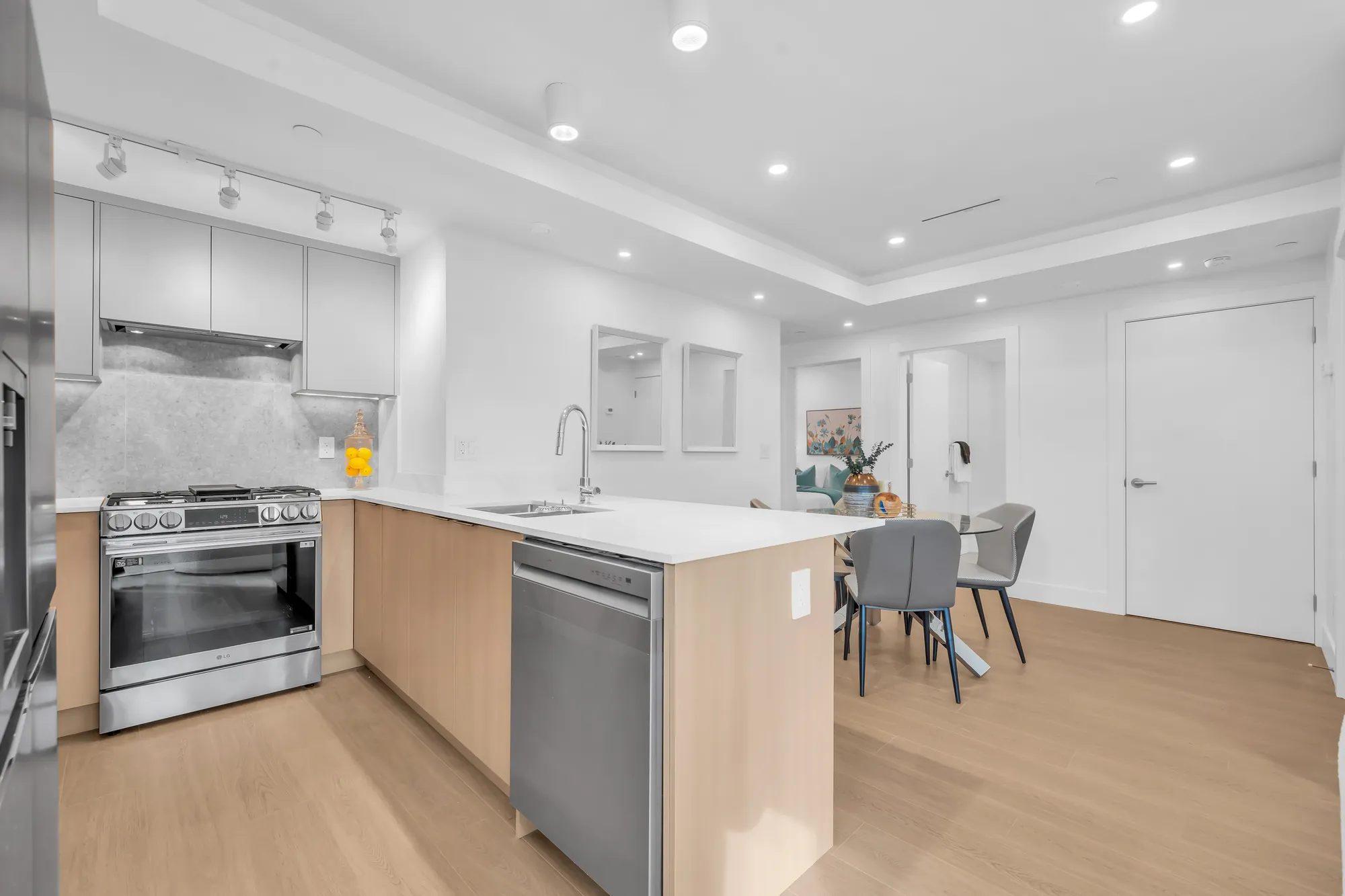 The kitchen from the dining room: a stainless range, a dishwasher, the peninsula and the dining table