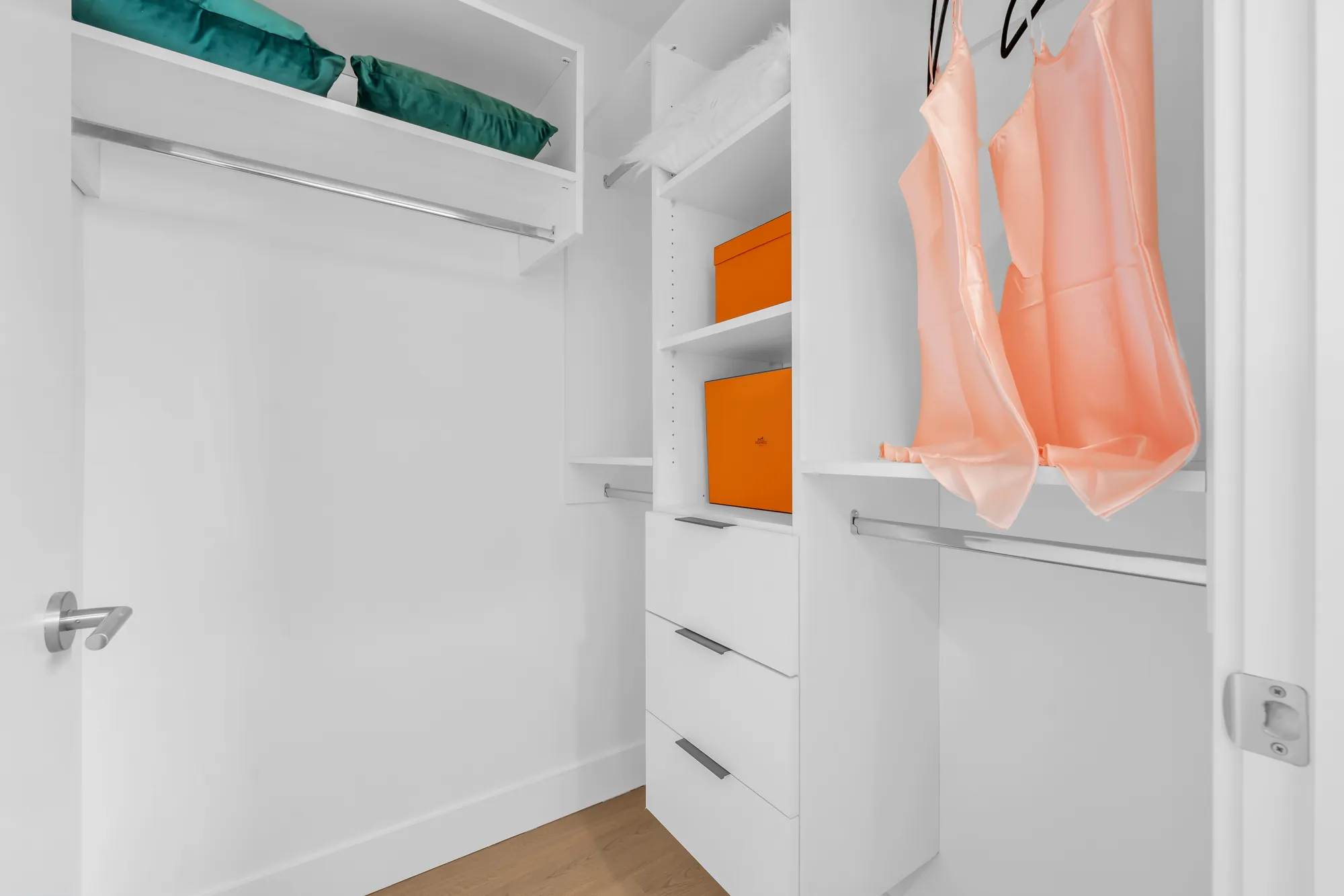 The walk-in closet: white shelves, drawers and hanging rails