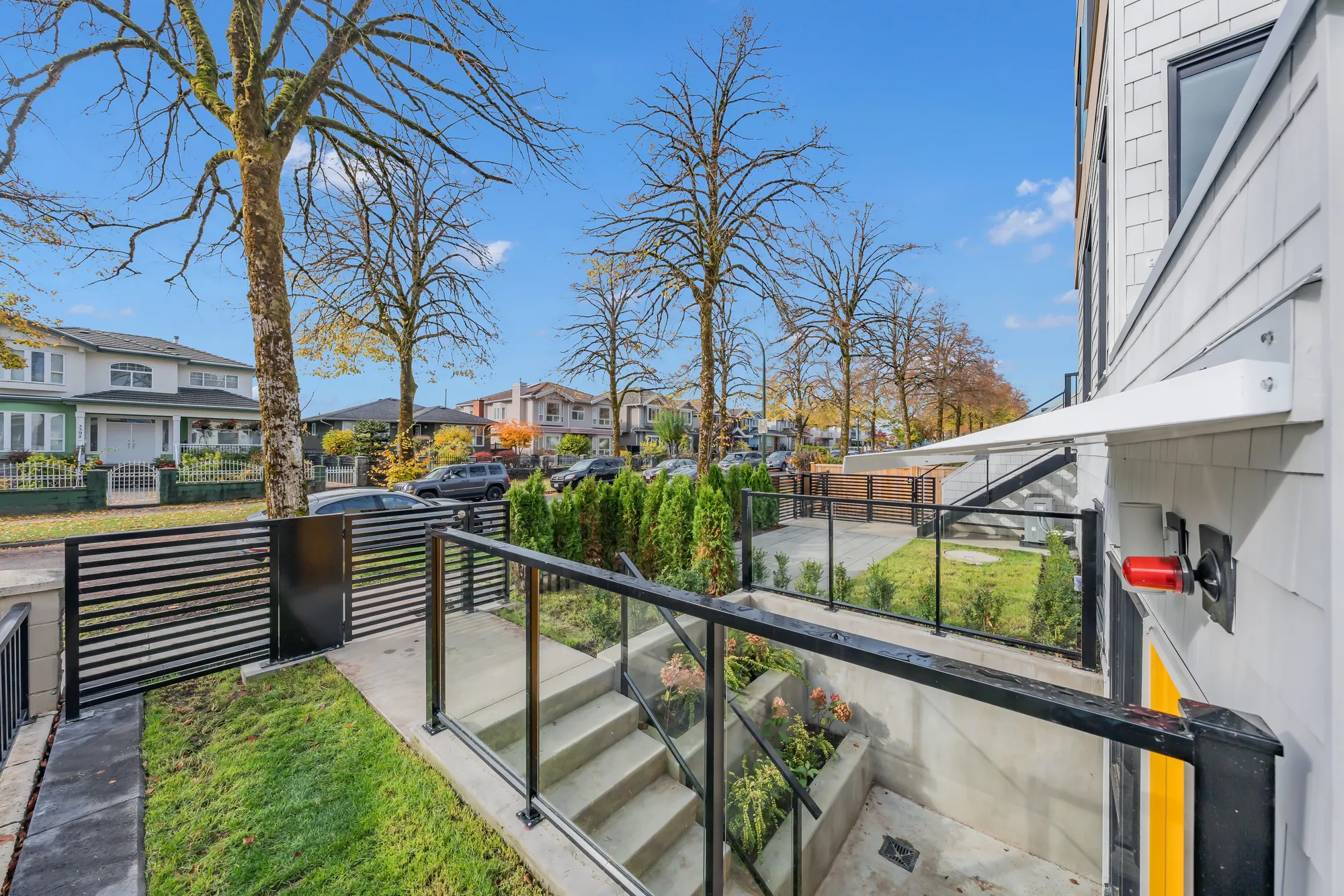 The front yard toward the street: the black gate, the railing over the patio, the trees along Price Street